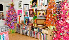 brightly colored christmas trees in a room with pictures on the wall and bookshelves