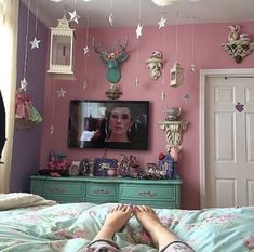 a person laying on top of a bed in front of a tv mounted to the wall