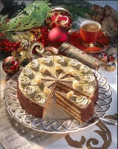 a cake with slices cut out on a platter next to christmas decorations and coffee