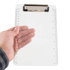 a hand holding a clipboard with a ruler on it