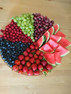 a platter filled with watermelon, grapes, strawberries and other fruit