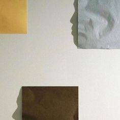 three pieces of brown paper on a white wall