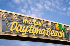 a welcome to daytona beach sign on a bridge