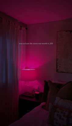 a pink light shines in the corner of a room with a bed and window