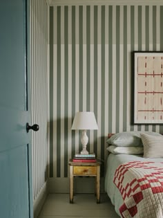 a bedroom with striped wallpaper and a small table in the corner next to it