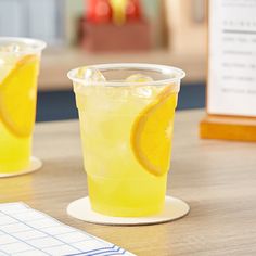 two glasses filled with lemonade sitting on top of a table