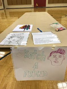 a table with some drawings on it in the middle of a gym floor that is covered in wood planks