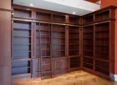 an empty room with wooden bookshelves and ladders in the middle of it