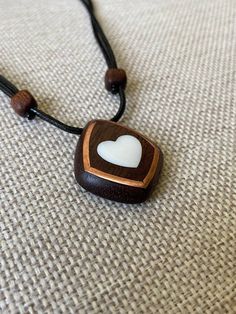 Size: 3.5 x 3 cm Immerse yourself in a world of romance with our elegant mahogany heart pendant with mother-of-pearl inlays. Every detail of this unique decoration embodies warmth and tenderness, creating a unique atmosphere. Our artisans carefully craft the pendant by hand, using only the finest materials. Mahogany adds natural warmth and sophistication, reproducing its unique patterns and textures. Mother-of-pearl inserts give the product a magical shine and a gentle glow that attracts attenti Brown Square Pendant Jewelry For Gift, Handmade Mahogany Jewelry Gift, Mahogany Handmade Jewelry For Gift, Handmade Mahogany Jewelry For Gift, Unique Mahogany Jewelry For Gift, Handmade Mahogany Necklace For Gift, Unique White Heart-shaped Necklace, Valentine's Day Brown Heart Charm Jewelry, Mother Of Pearl Heart Pendant Jewelry Gift