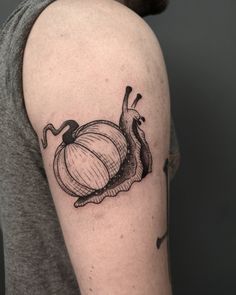 a man's arm with a tattoo on it that has a snail and pumpkin