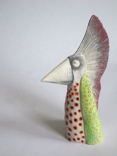 a ceramic bird with orange, green and white feathers