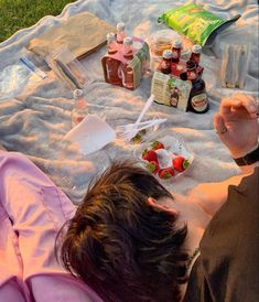 a woman laying on top of a blanket covered in food and confection bottles