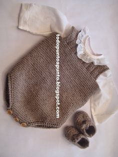 a knitted baby sweater and booties laying on top of a white sheet