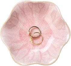 two gold wedding rings in a pink flower shaped bowl