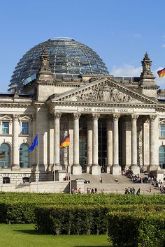 a large building with many flags flying in front of it's windows and roof