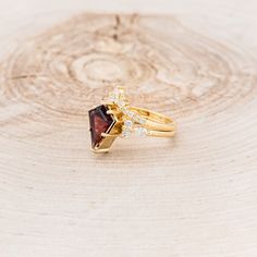 a close up of a gold ring with a garnet stone and diamonds on it