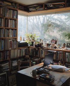 a room filled with lots of books and a laptop computer on top of a wooden table