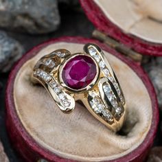 This awesome ring is centered with one (1) oval mixed cut natural ruby set into a bezel. The ring features a by-pass style shank accented with thirty-two (32) round brilliant cut diamonds set into channels. The ring measures 14.6mm at the top, rises 4.9mm above the finger, tapering to 3.3mm wide and 1.1mm thick at the base of the shank. This ring is currently a size 6. The bezel around the ruby is ever so slightly less smooth than we would like to see, but it is not overly noticeable and there a Oval Ruby Ring With Vvs Clarity Diamond, Luxury Oval Rings With Rose Cut Diamonds And Ruby, Oval Lab-created Ruby Rings With Rose Cut Diamonds, Vintage Oval Ruby Ring With Vvs Clarity, Oval Ruby Ring With Rose Cut Diamonds For Anniversary, Heirloom Style Oval Lab-created Ruby Ring, Heirloom Oval Lab-created Ruby Ring, Ruby Set, Rings Collection