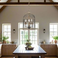 a large wooden table sitting in a kitchen under a light hanging from a ceiling fixture