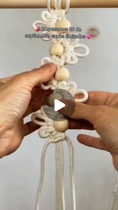 two hands are working on an object with yarn and beads in the shape of balls