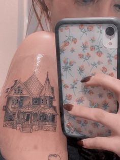 a woman is holding up her phone case to show the tattoo on her arm