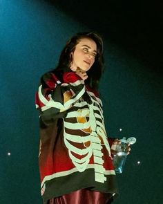 a woman standing in front of a stage wearing a skeleton shirt and red leather skirt