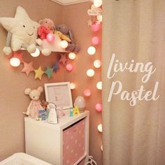 a child's bedroom decorated in pink and white with lights on the wall above