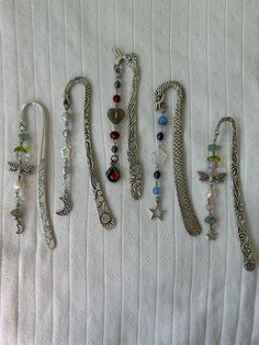 several different bracelets are lined up on a white sheet with beads and charms hanging from them