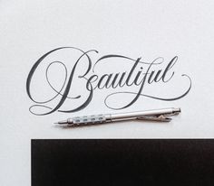 the word beautiful written in cursive writing with a pen on top of it