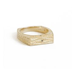 a gold ring with an engraved design on the front and sides, set against a white background