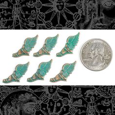 six small green angel wings sitting next to a quarter dollar coin on a black and white background