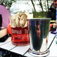 there is a glass and a bottle sitting on the picnic table next to each other