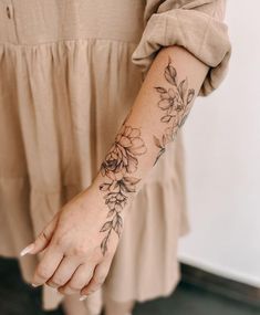 a woman with a flower tattoo on her arm holding onto the hand of another person