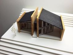 two small model houses sitting on top of each other in front of a white wall