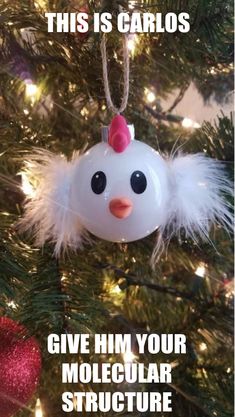 a white ornament hanging from a christmas tree decorated with lights and feathers in the shape of a chicken