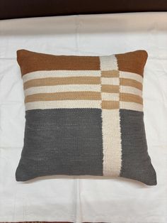 a brown and white pillow sitting on top of a bed