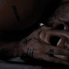 a man with tattoos on his face and hands is laying down next to another person