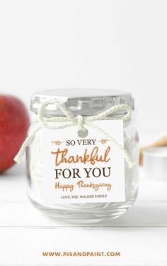 a glass jar filled with some kind of food next to an apple and cookie tin