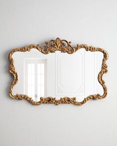 a mirror that is on the wall with an ornate frame and gold trimmings