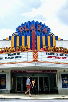 two people walking in front of a theater