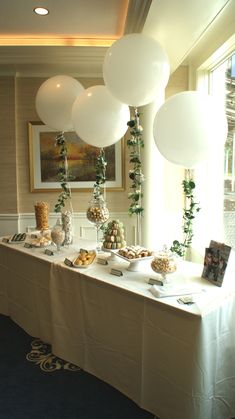 a long table with balloons and desserts on it