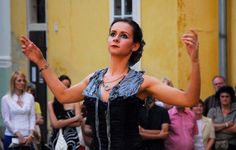 a woman in a black dress is holding her arms out to the side while people are looking on