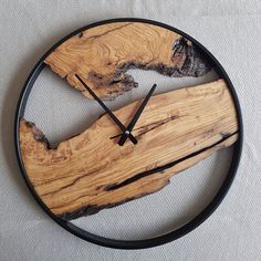 a clock made out of wood and metal on a white tablecloth with a black frame