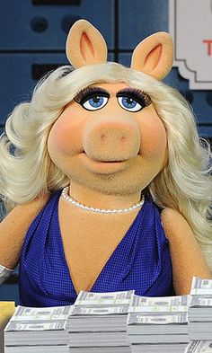 the miss piggy doll is sitting in front of stacks of money