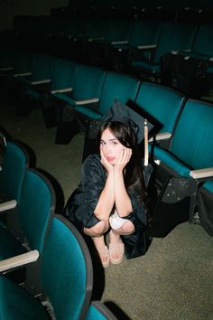 a young woman sitting in an auditorium with her graduation cap on