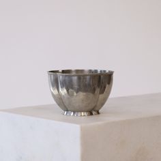 a silver bowl sitting on top of a white block