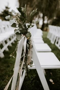 white folding chairs with greenery tied to them