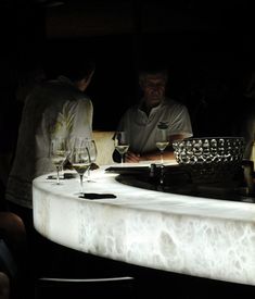 people are sitting at a bar with wine glasses on the counter and one man is looking at his cell phone