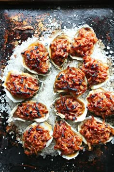 an overhead view of several open oysters on a baking sheet with salt and pepper