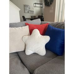 a star pillow sitting on top of a gray couch next to a blue and red pillow